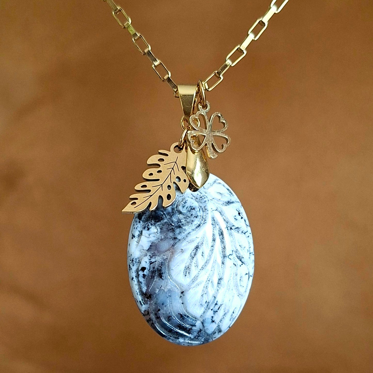 Collier en opale dendrite ciselée motif feuille avec breloques feuille et trèfle dorés.