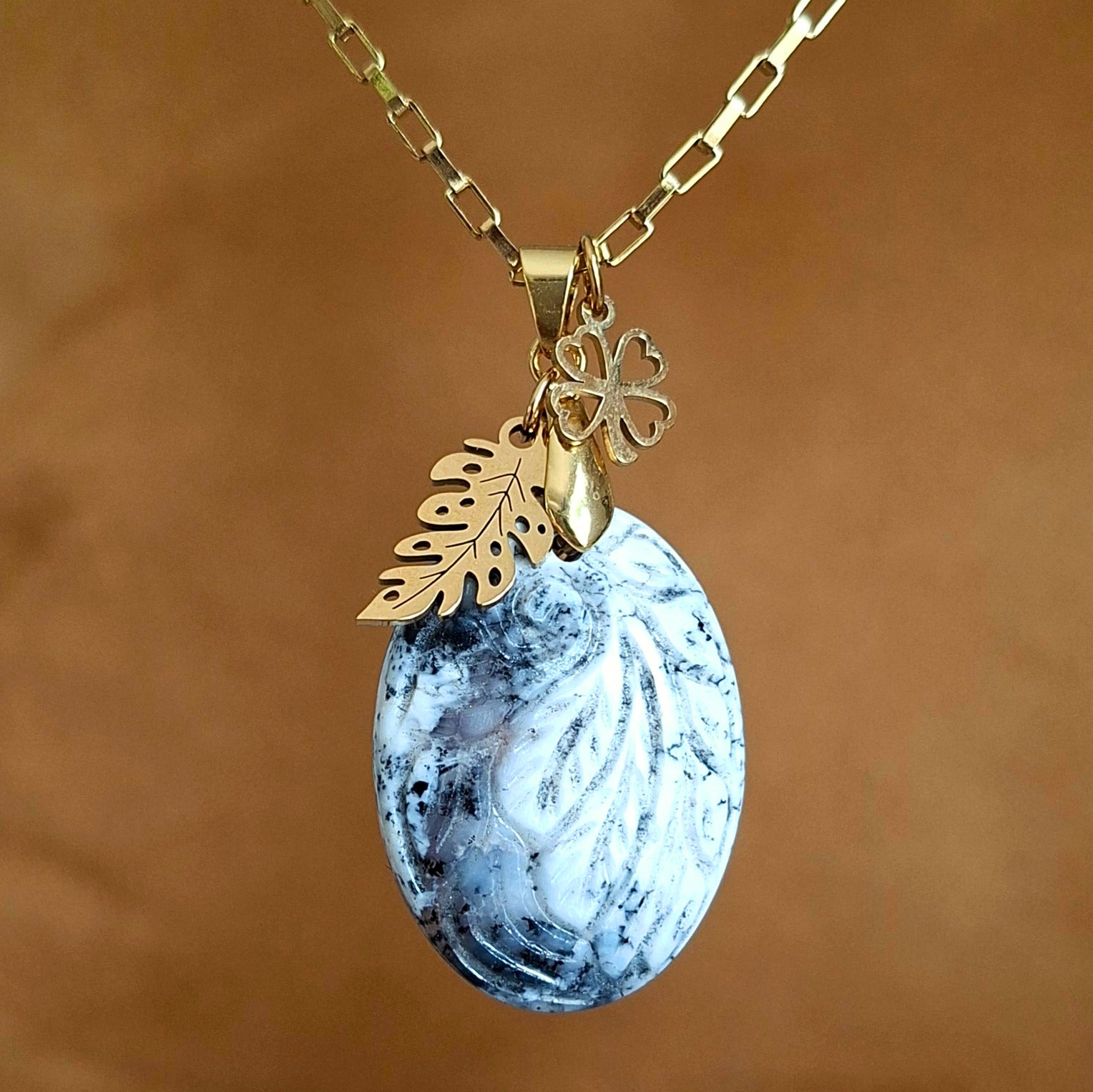Collier en opale dendrite ciselée motif feuille avec breloques feuille et trèfle dorés.