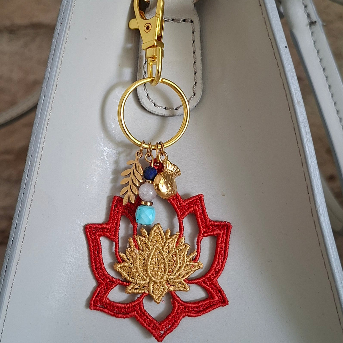 Grigri de sac Lotus artisanal accroché à un sac gris clair