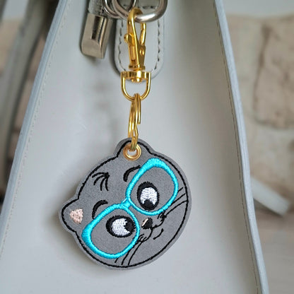 Porte clé chat brodé à lunettes bleues attaché à un sac à main
