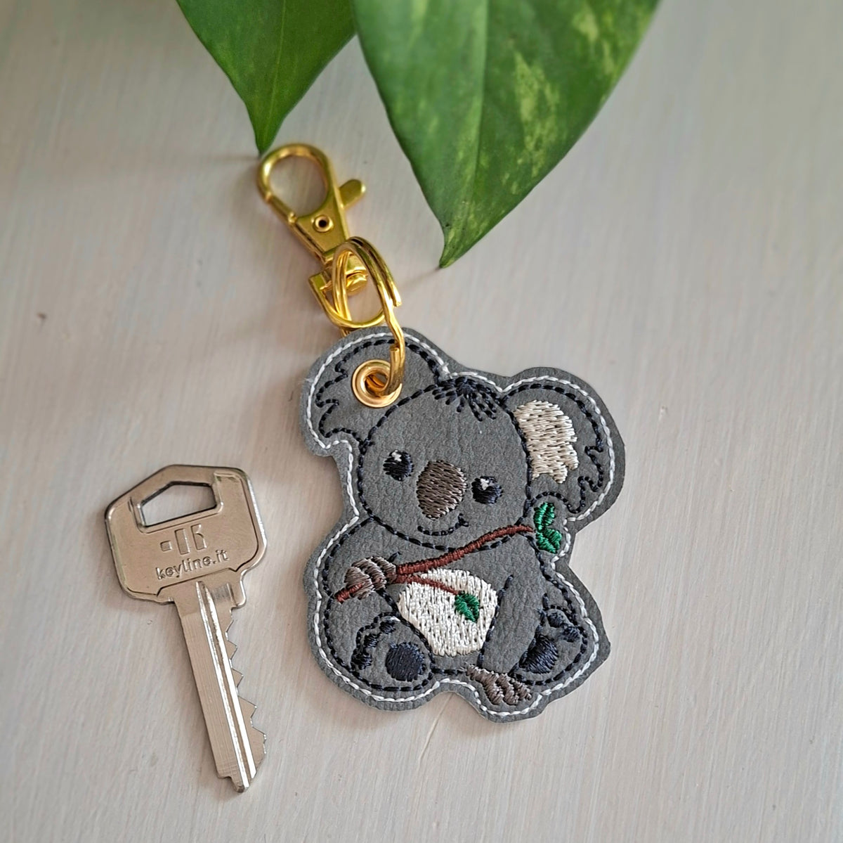 Détail de la broderie du porte-clés koala sur simili-cuir gris