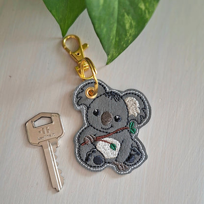 Détail de la broderie du porte-clés koala sur simili-cuir gris