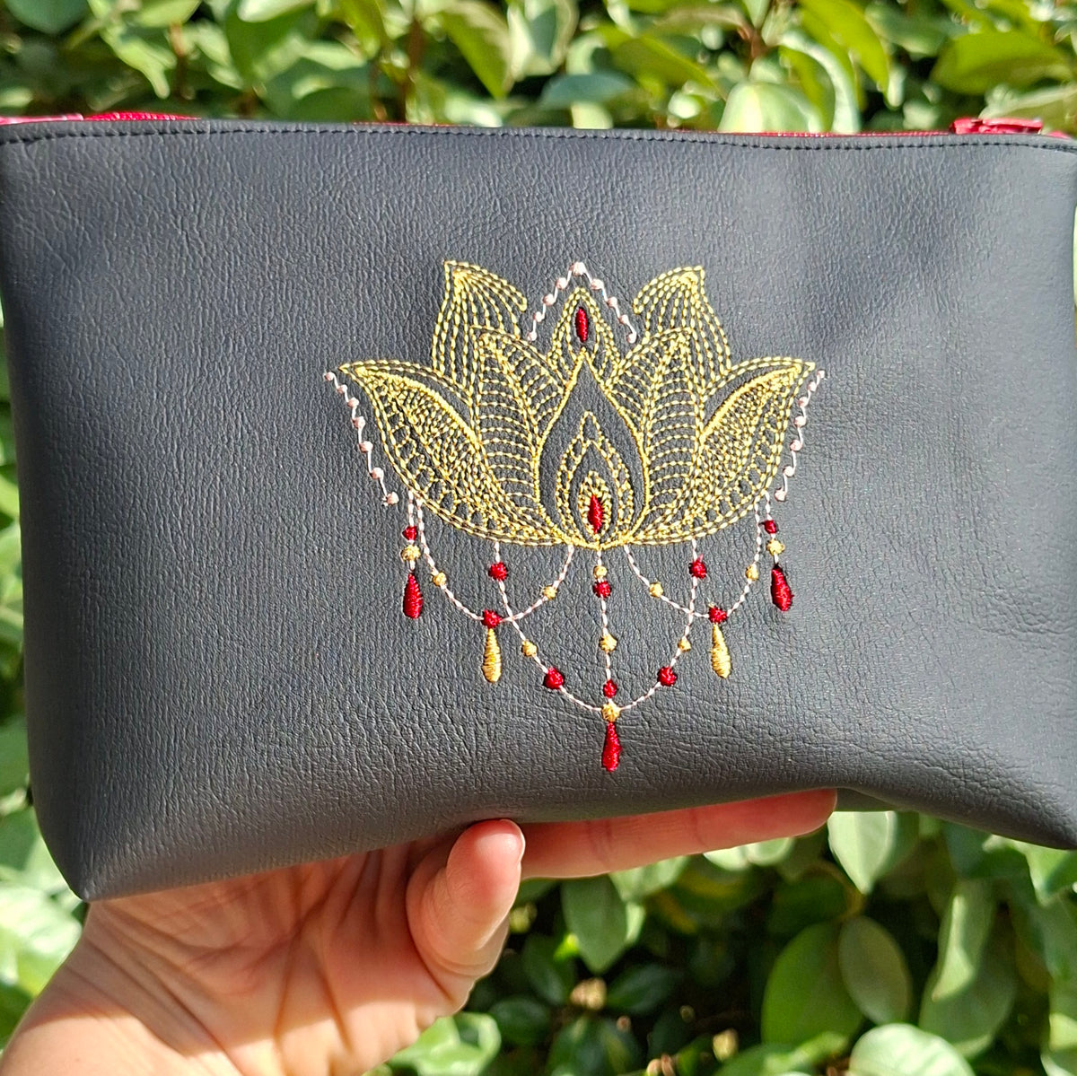 Trousse femme brodée lotus en simili cuir noir tenue en main